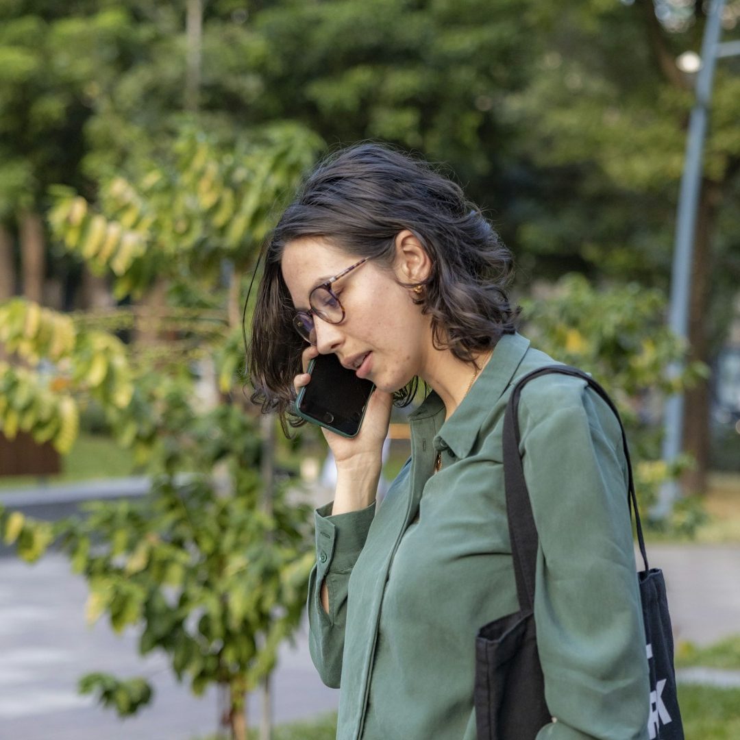A woman on a phone call with her Coach during a walk in the park